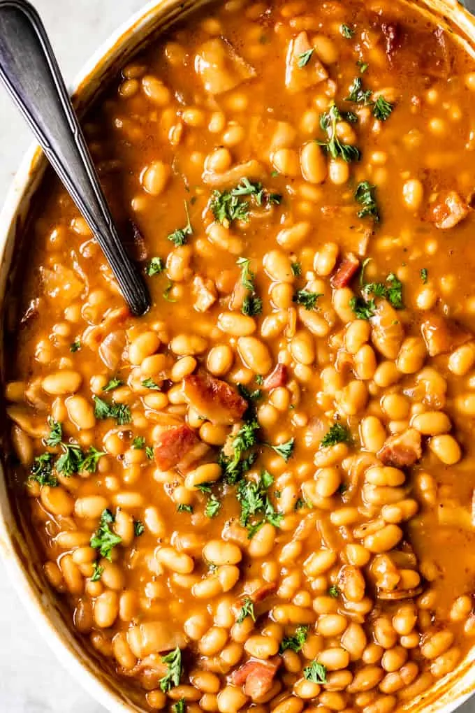 Overhead view of baking dish with baked beans, topped with fresh parsley as a garnish.