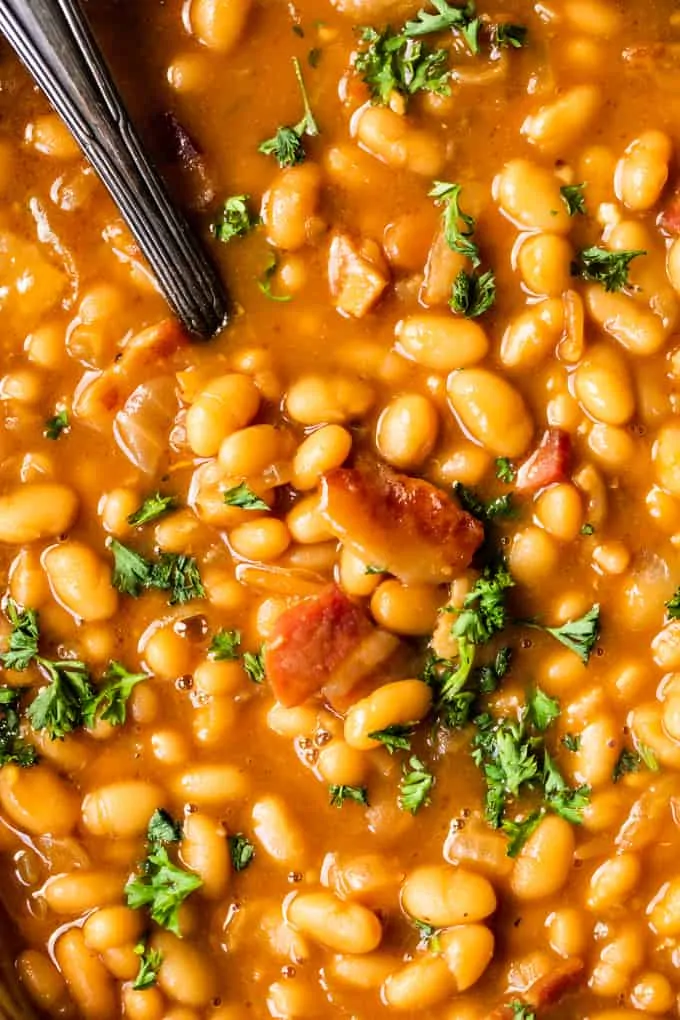 Up close view of baked beans in a thick syrup with bits of crispy bacon.