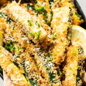 Basket filled with zucchini fries, showing a cup of ranch dressing and a lemon wedge on the side.