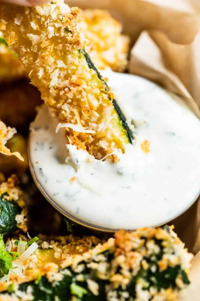 Zucchini fry being dipped into homemade ranch dressing.