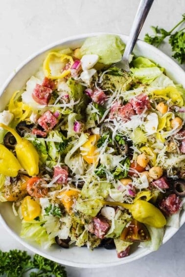 Italian chop salad, lettuce with diced salami, tomatoes, chick peas, tomatoes, red onion, and more all drizzled with Italian dressing, topped with whole pepperoncinis.