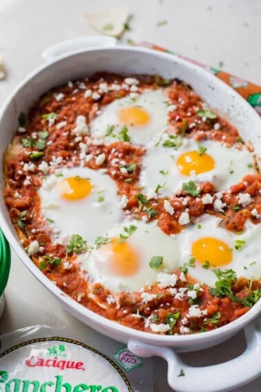 Huevos Rancheros breakfast casserole in a white casserole dish, topped with fresh diced cilantro.