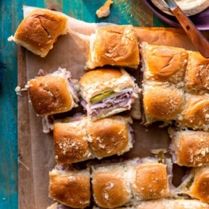 Overhead shot of a tray of cuban sliders that have been sliced apart, showing stretchy melty cheese attaching them.