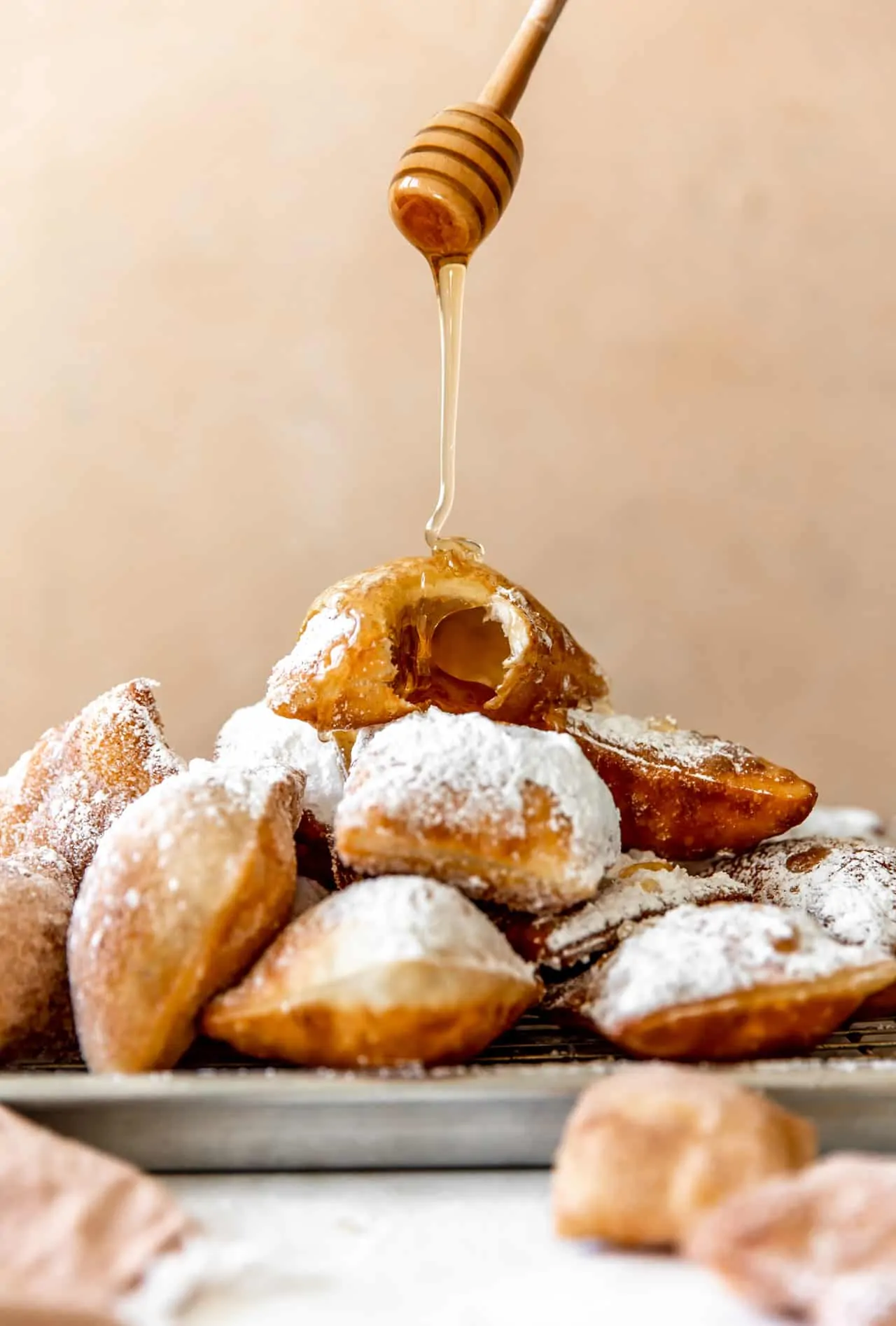 Stacked sopapillas with the top one showing a hollow interior. A drizzle of honey coming down onto the top so papilla.