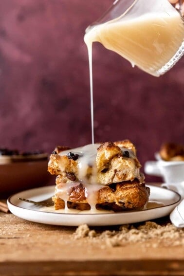 Vanilla syrup pouring over the top of a piece of bread pudding with raisins.