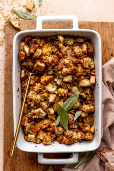 Dish with baked cornbread dressing topped with fresh sage leaves.