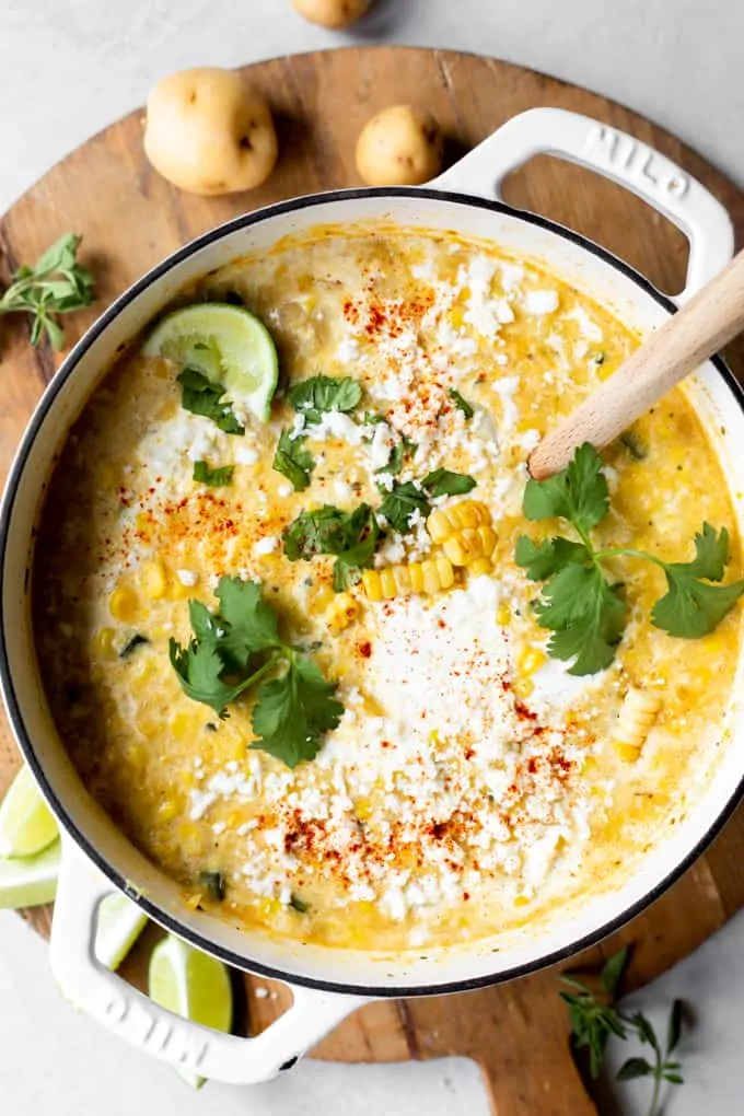 Pot filled with Mexican street corn chowder topped with Crema, queso fresco, and fresh cilantro. 