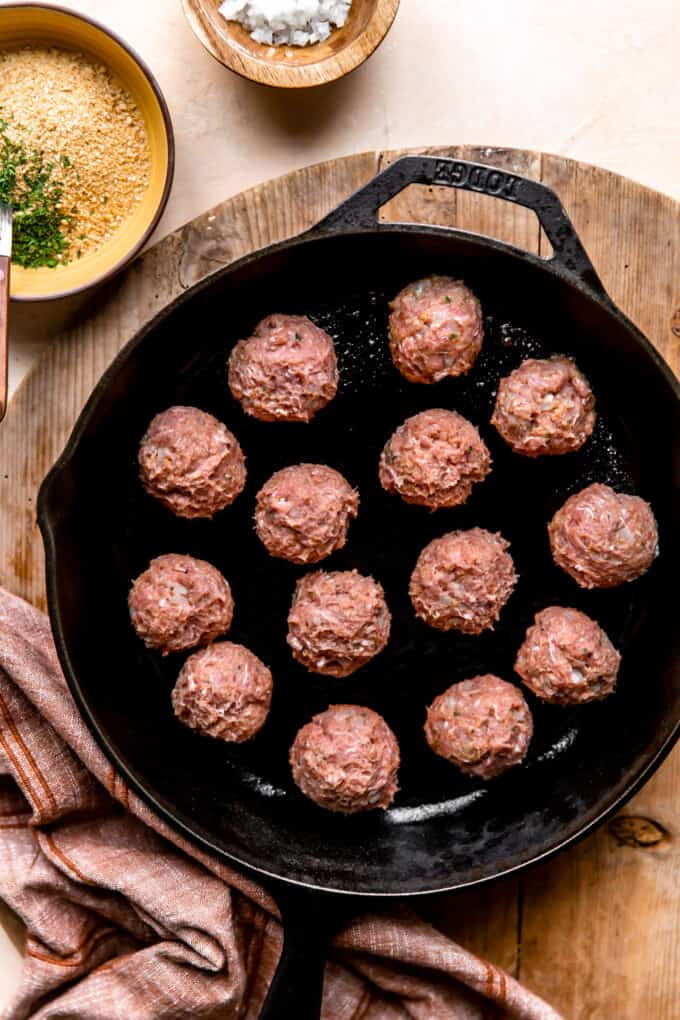 Turkey meatballs in a large cast iron skillet for cooking.