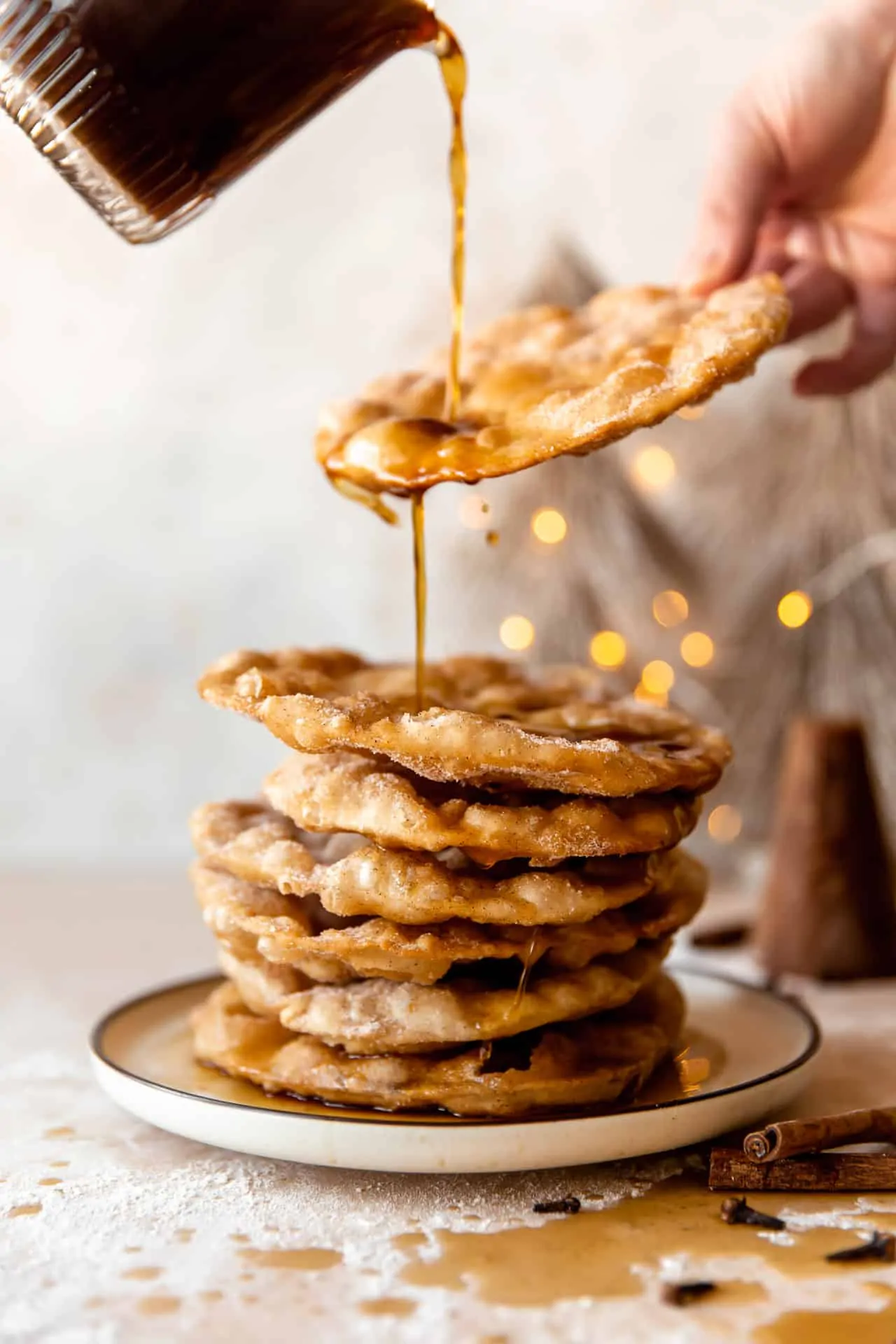 Piloncillo syrup drizzling over a stack of freshly fried bunuelos. 