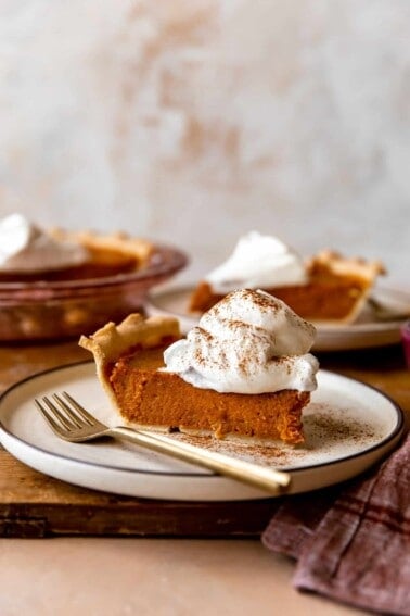 Slice of sweet potato pie with a swirl of whipped cream on top.