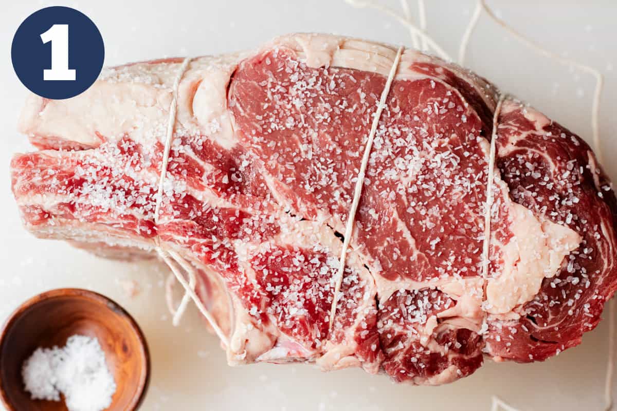 Salted prime rib roast tied together with twine.