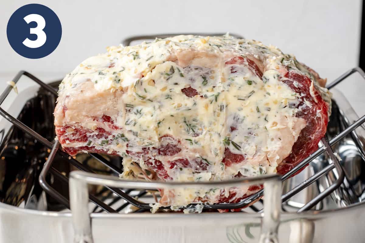 Prime rib in a roasting rack rubbed with garlic herb butter.