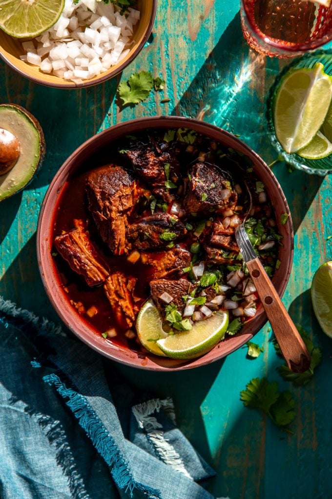 Bowl filled with birria de res served as a stew topped with cilantro and onions.