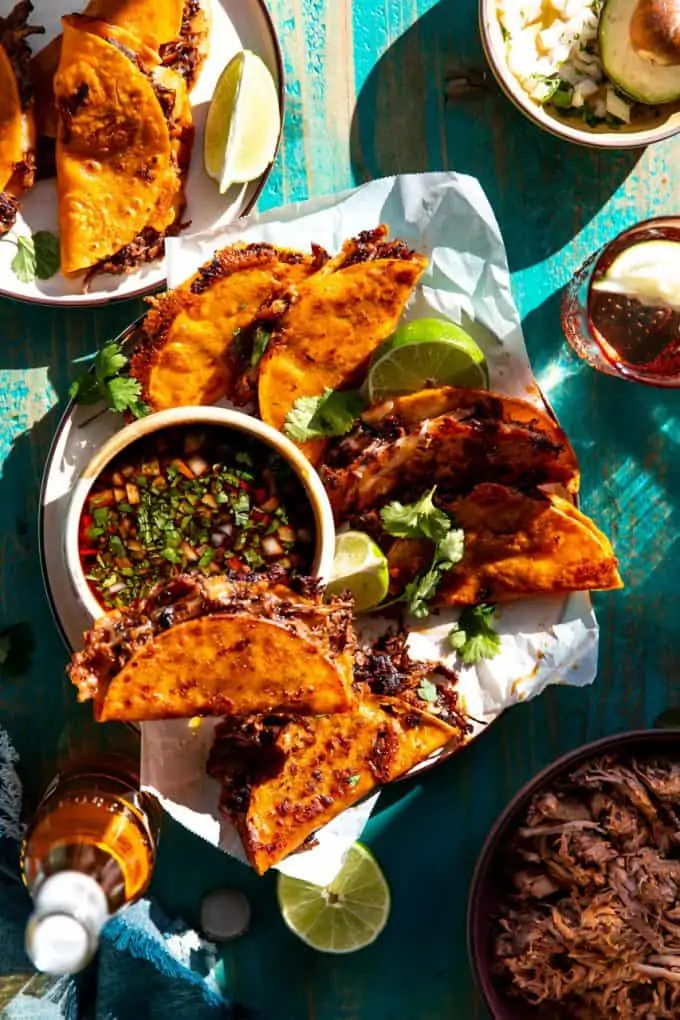 Plate filled with birria tacos and a bowl of consommé.
