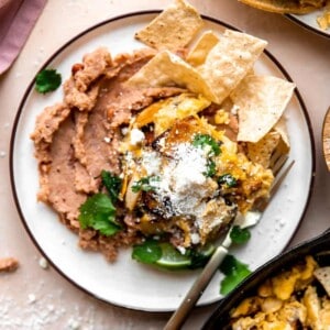 Overhead picture of Migas served over refried beans on a white plate.