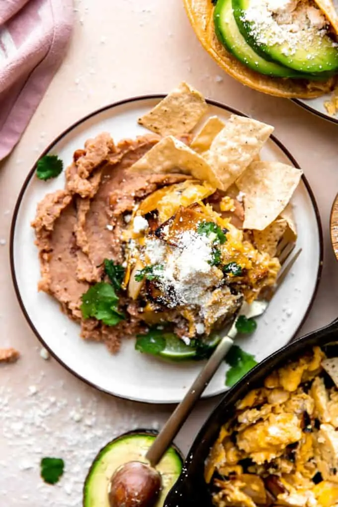 Overhead picture of Migas served over refried beans on a white plate.