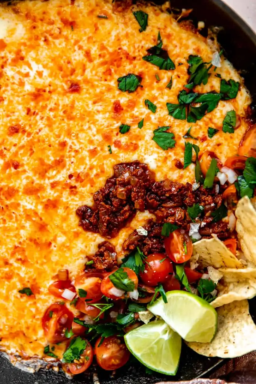 Up close view of queso funded. Showing melted cheese and chorizo, topped with pico de Gallo and cilantro.