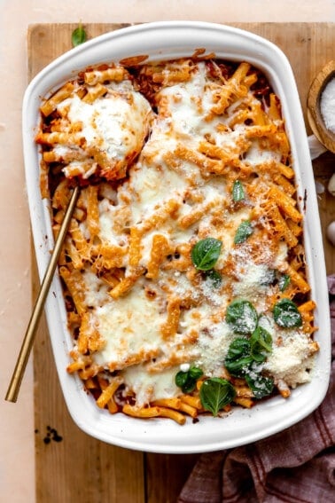 Baked ziti in a baking dish served with a large spoon.