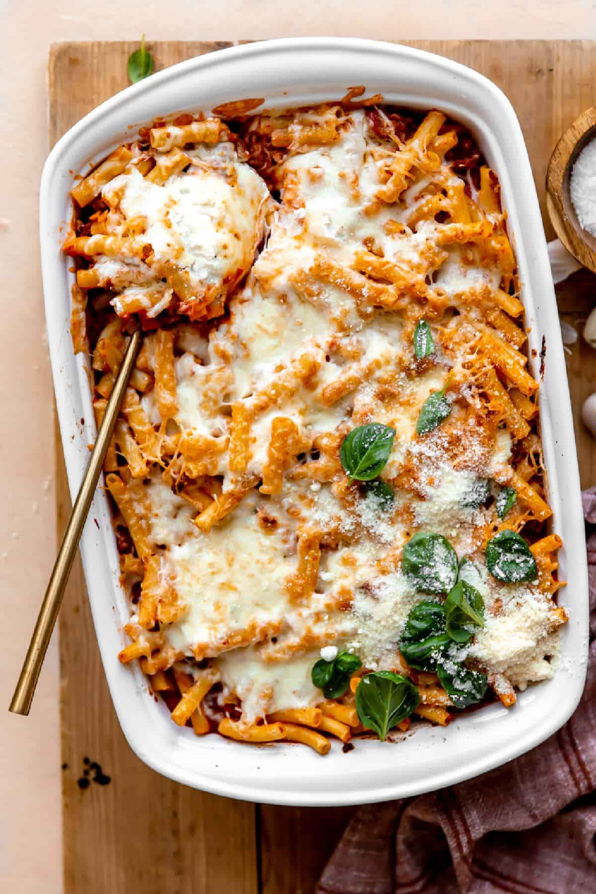 Baked ziti in a baking dish served with a large spoon.