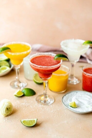 Frozen margaritas with lime wedges on the side.