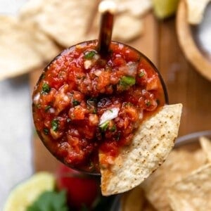 Overhead view of a jar of homemade sals with a tortilla chip being dipped in.