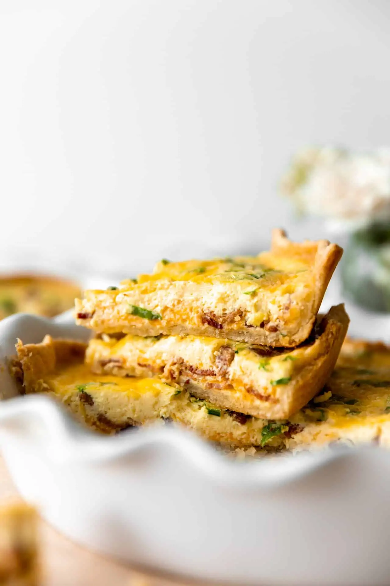 Stacked up slices of quiche in a pie dish. 