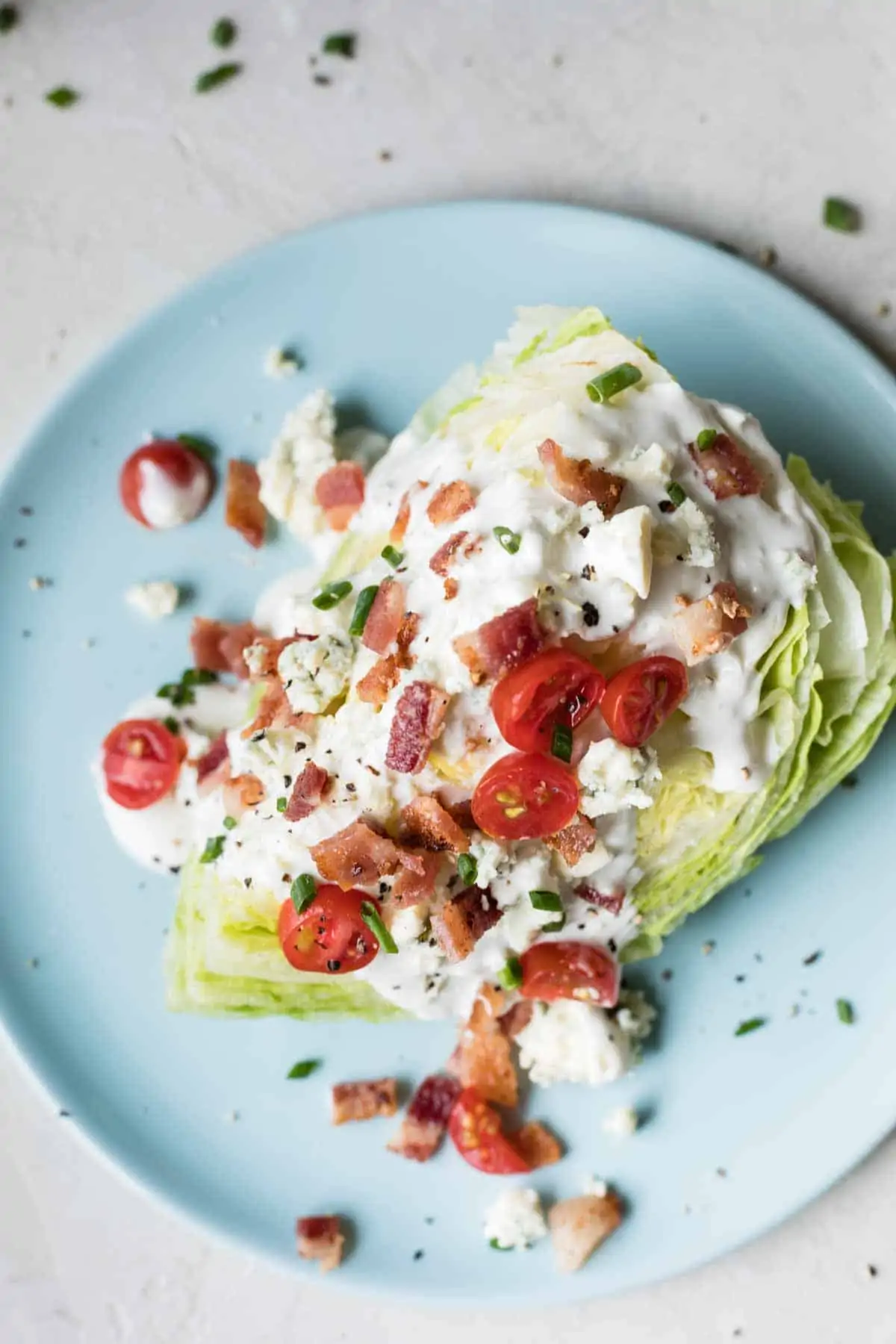 Overhead view of dressing and toppings on a wedge of lettuce for a salad.