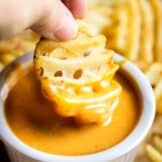 Dipping a waffle fry into a small bowl of homemade Chick Fil A Sauce.
