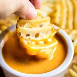 Dipping a waffle fry into a small bowl of homemade Chick Fil A Sauce.
