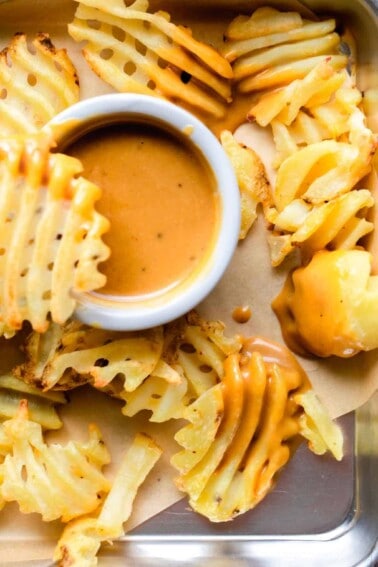 Tray filled with waffle fries and a bowl of homemade Chick Fil A Sauce.