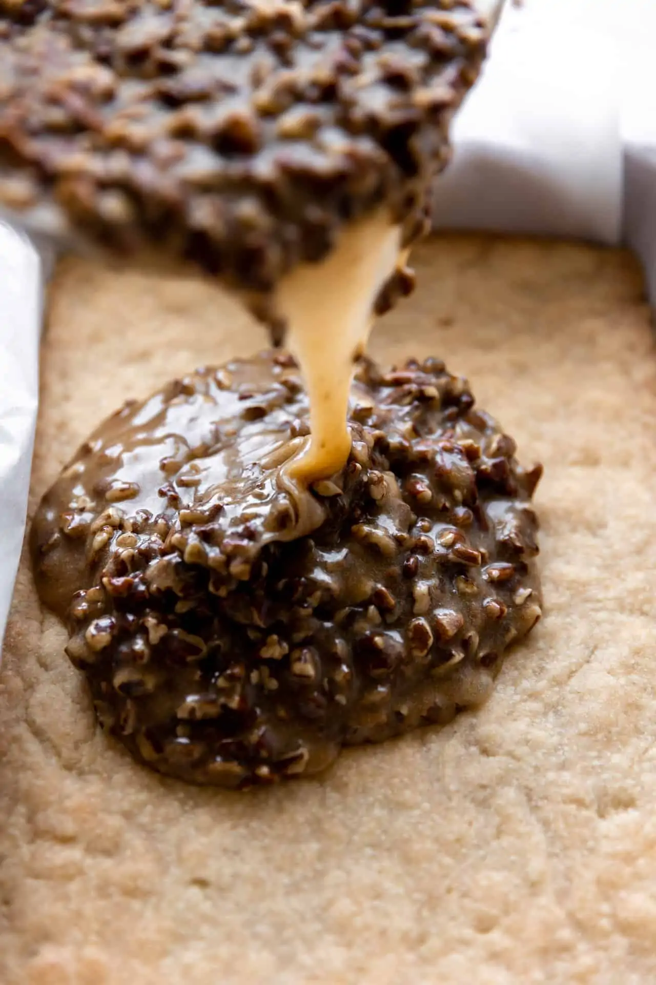 Pouring pecan pie topping over shortbread cookie crust. 