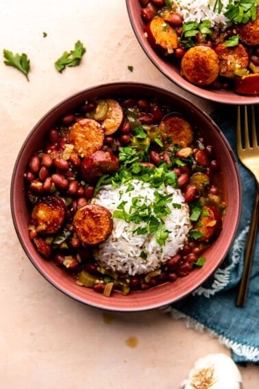 overhead view of a bowl of red beans and rice served with fresh parsley.