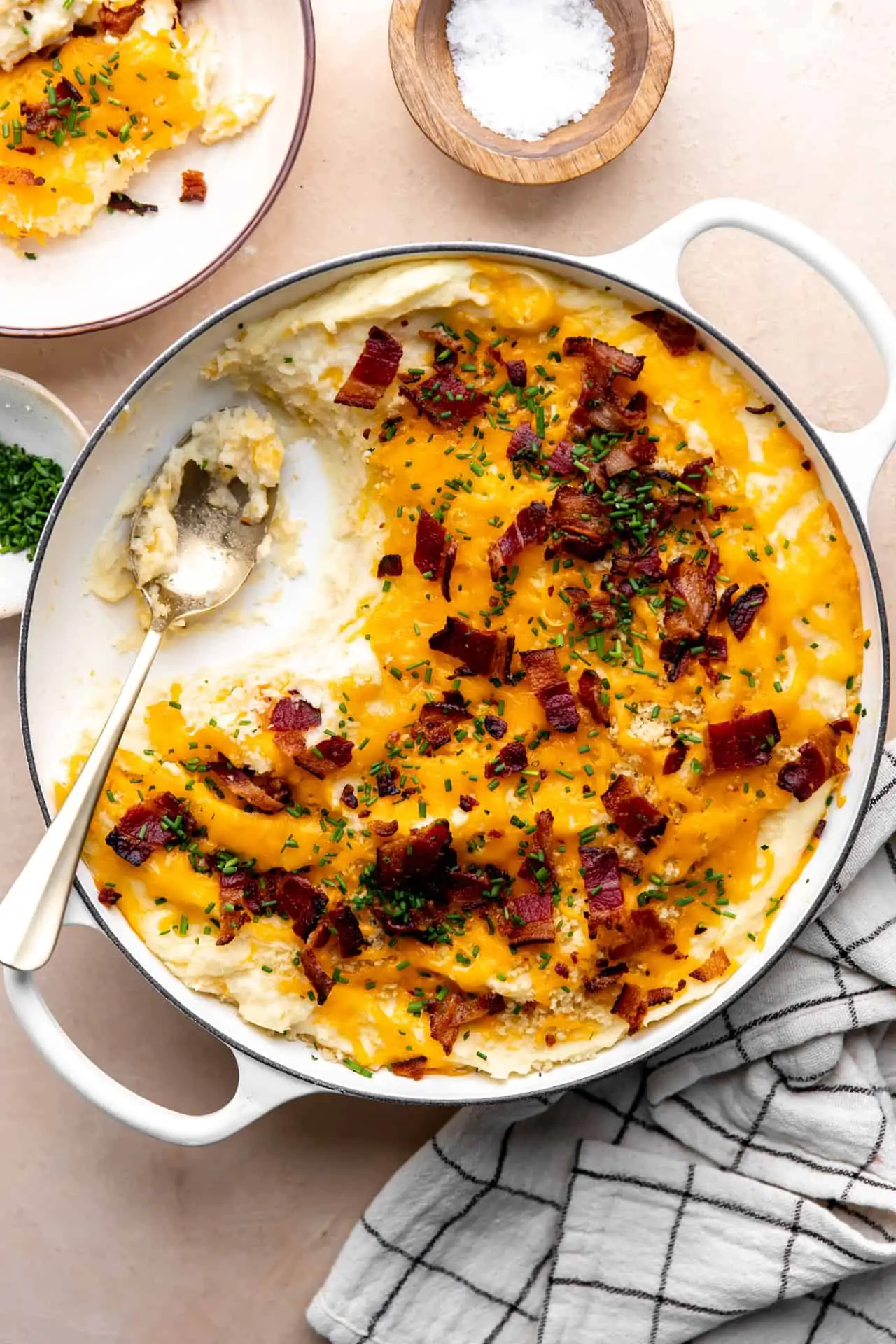 Dish of loaded potato casserole with servings removed by a spoon.