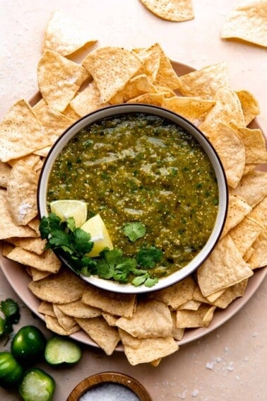 Bowl of homemade salsa verde surrounded by tortilla chips.