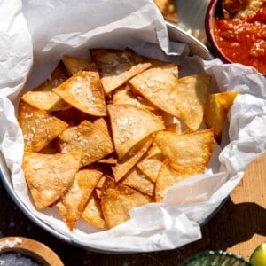 Basket of homemade salted tortillas chips served with salsa and guacamole.