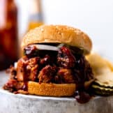Smoked BBQ Brisket sandwich made with sauce, pickles and sliced onion. Served with chips