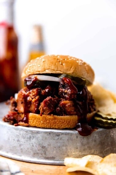 Smoked BBQ Brisket sandwich made with sauce, pickles and sliced onion. Served with chips