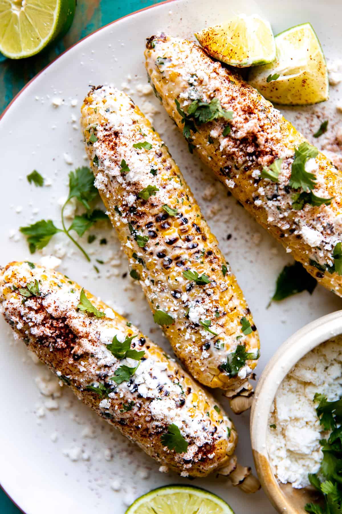 Plate with elotes topped with crumbled cotija and chopped cilantro.