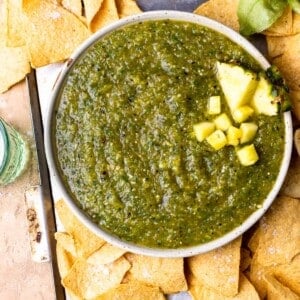 Bowl of pineapple salsa served with tortilla chips and lime wedges.