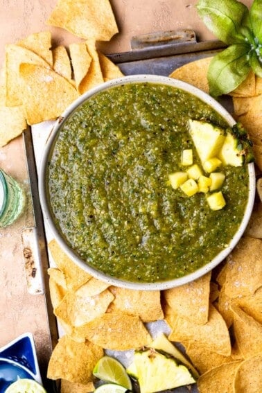 Bowl of pineapple salsa served with tortilla chips and lime wedges.