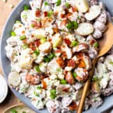 Overhead view of creamy red potato salad being served with a spoon.