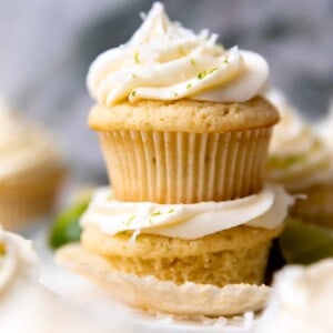 Stacked coconut lime cupcakes topped with coconut cream cheese frosting.