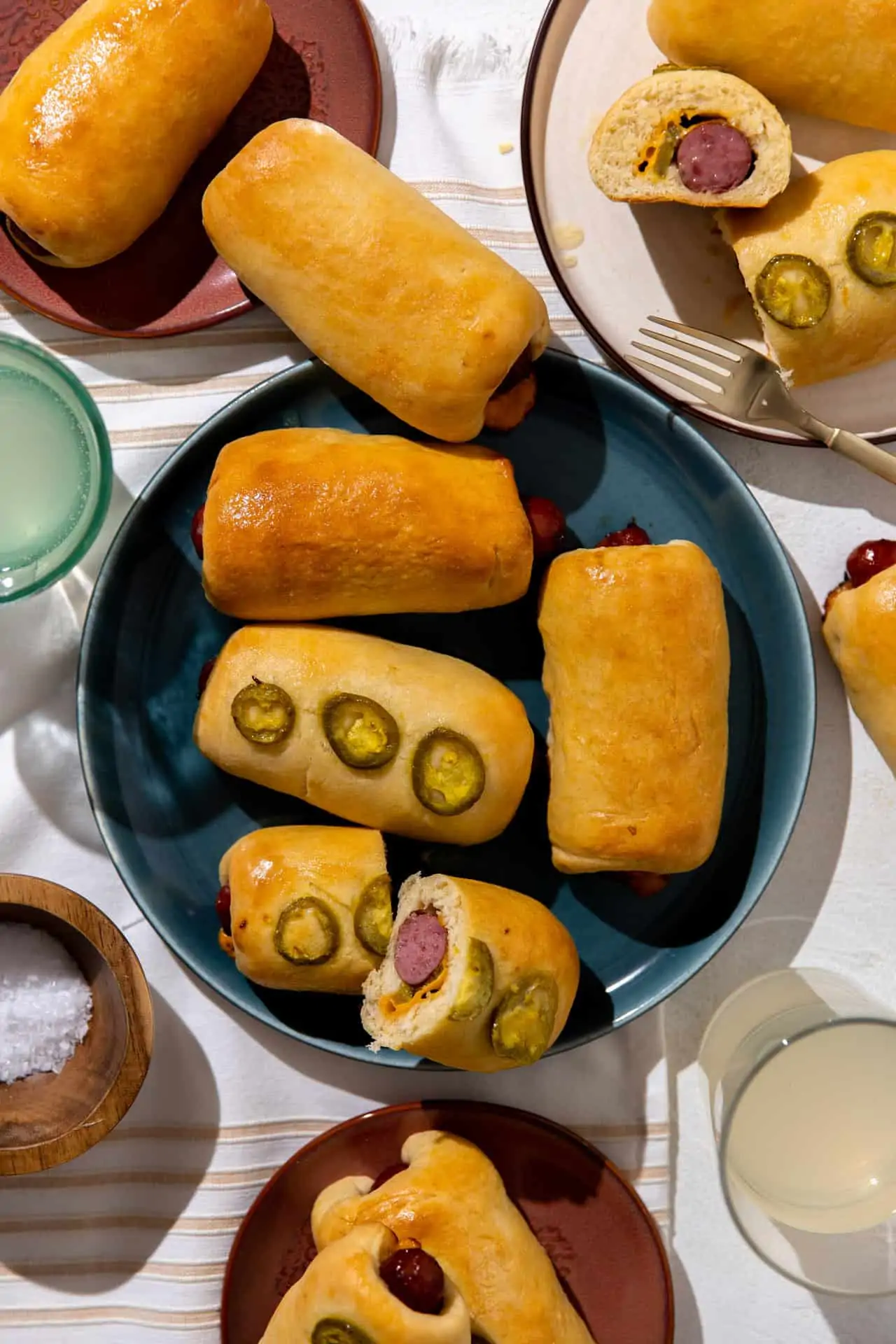 Texas style kolaches on a plate, topped with jalapeños and cut open to show the cheese and jalapeño inside.
