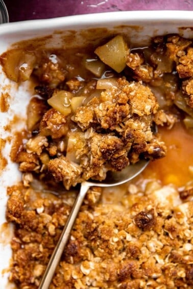 Baked apple crisp being served with a large spoon.