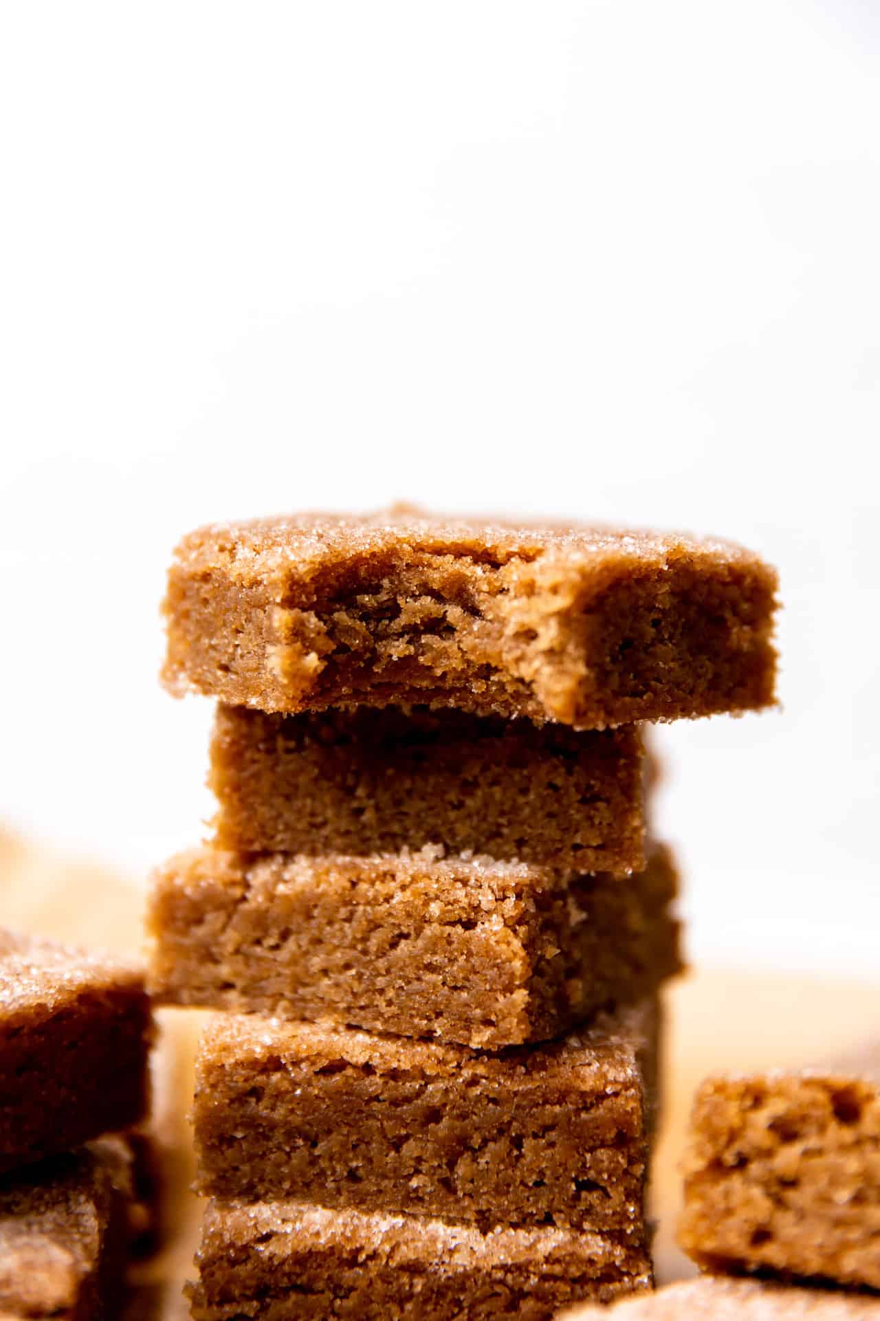 Up close view of cinnamon churro bars stacked with bite out of the top one.