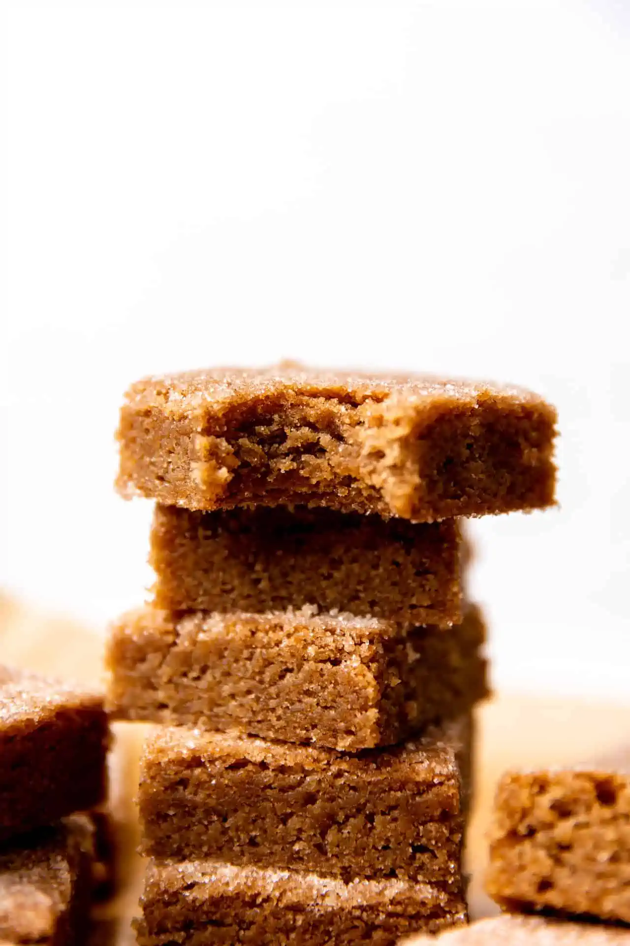 Up close view of cinnamon churro bars stacked with bite out of the top one.