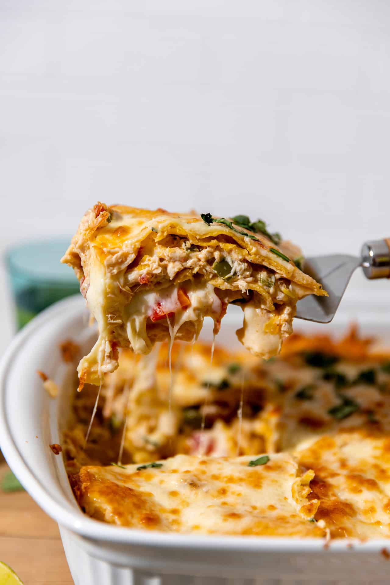 Spatula serving a slice of king ranch chicken casserole showing melted cheese.