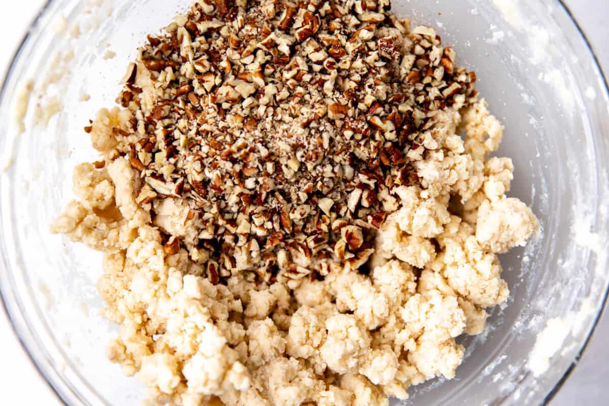 Cookie dough for Mexican wedding cookies with chopped pecans being added.