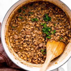 Pot filled with cooked black eyed peas with chunks of ham and bacon, topped with cilantro.