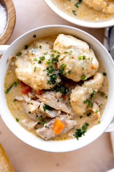 Bowl of chicken and dumplings topped with fresh chives.